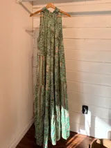 Vestido largo verde agua con estampado floral, cuello halter y corte escalonado.