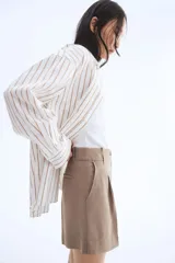 Short color beige de corte sastrero, con cierre y botón, bolsillos al bies y bolsillo trasero decorativo. Piernas con pinzas y pliegues adelante y atrás.
