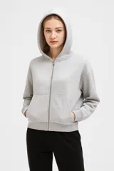 Campera gris con capucha y cierre frontal, de manga larga y corte cropped.