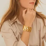 Brazalete rígido dorado con textura irregular.