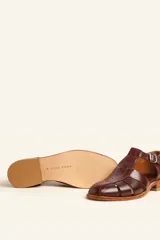 Sandalia marrón de cuero vacuno con diseño de tiras entrecruzadas, hebilla lateral y taco bajo de 2,5 cm.