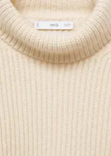 Sweater color crema de punto grueso con cuello alto.