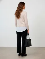 Buzo de hilado fino color beige con cuello y ruedo de gasa blanca que simula una camisa debajo. Presenta escote en V y mangas largas.