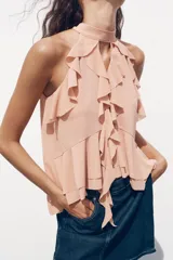 Top color rosa viejo de cuello halter ajustable con lazadas. Detalle de abertura en el delantero y volantes en el mismo tejido.
