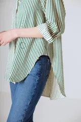 Camisa holgada de manga larga con rayas verticales verdes y blancas. El ruedo es más largo en la parte trasera.
