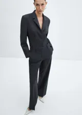 Americana entallada color gris oscuro, con solapas de muesca, manga larga con puños abotonados, bolsillo de ribete en el pecho, forro interior y cierre frontal con botones. Diseño body.