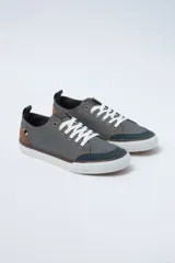 Zapatillas acordonadas de lona color gris con detalles en marrón y azul marino. Suela de goma blanca.