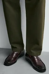 Mocasín de cuero color borgoña, con antifaz y suela negra en contraste.