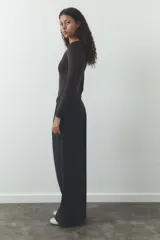 Pantalón negro de tiro alto, corte ancho y largo midi. Incluye bolsillos delanteros, pinzas y cinturón de la misma tela.