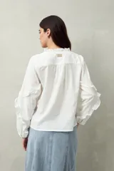 Blusa color amarillo pálido de manga larga con escote en V, mangas abullonadas con volados y botones forrados.
