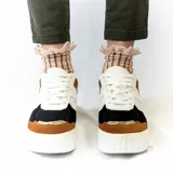 Zapatillas urbanas con plataforma, color blanco con detalles en negro, marrón y dorado.