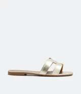 Sandalia plana de cuero sintético color negro, con puntera cuadrada y tiras anchas cruzadas en el empeine.