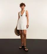 Vestido corto de playa confeccionado en viscolino color crudo, con sisas profundas, escote en V y detalle de vieses contrastantes en color negro.