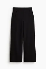 Pantalón negro de punto grueso, tiro alto con elástico oculto, botones decorativos adelante y piernas rectas de corte holgado.