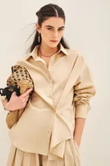 Camisa beige de poplin amplia, con botones laterales para abotonar de forma cruzada.