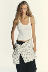 Top blanco de morley con escote redondo y tirantes. Detalle de flor en relieve combinada al tono.