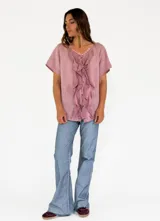 Camisa de lino y algodón color rosa claro, con cuello en V, mangas cortas y volados frontales.