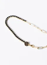 Pulsera dorada con una mitad de eslabones tipo clip y otra mitad con una hilera de zirconias negras.