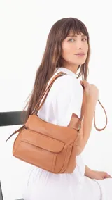 Bandolera de cuero sintético color marrón, con dos bolsillos frontales, uno con tapa y cierre. Interior espacioso con bolsillos.