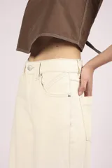 Pantalón de jean color crudo, de corte palazzo y tiro alto, con bolsillos delanteros y traseros, y costuras a la vista.