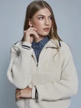 Sweater color crema de tejido grueso con medio cierre, cuello alto y detalles deportivos con rayas negras en puños y hombros.