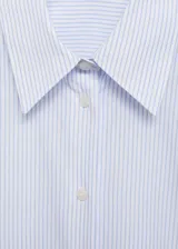 Camisa de popelina a rayas verticales celestes y blancas, de corte recto, con cuello camisero y mangas largas con puños abotonados.