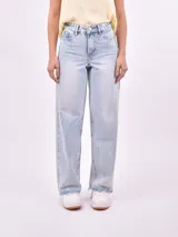 Jean de mezclilla celeste con lavado ácido y efecto desgastado. Modelo de tiro alto y corte ancho (wide leg) con ruedo deshilachado.