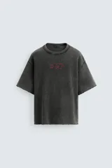 Camiseta negra con efecto lavado, corte boxy fit, cuello redondo y manga corta. Estampado rojo en el frente.