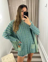 Sweater tejido de punto color fucsia con diseño de trenzas verticales en color naranja. Tiene cuello redondo y dos bolsillos frontales.