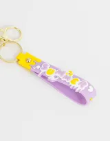 Llavero con dije de gatito dentro de una burbuja con base lila y correa de silicona lila con diseño de letras y dibujos en amarillo y blanco.