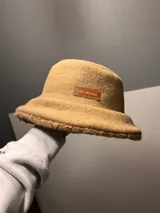 Gorro tipo bucket negro con textura de lana rizada y etiqueta con la inscripción "The Mood". Interior color marrón.