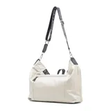 Bolso tote de cuero color taupe, con acceso superior con cierre y correa de hombro negra con letras blancas.