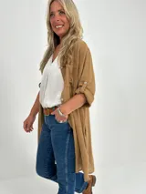 Sobrecamisa color camel de corte recto y largo midi, con cuello camisero, mangas largas con puños abotonados y bolsillos de parche en el pecho.