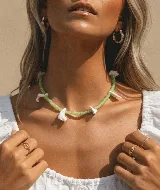 Collar corto de cuentas de cristal checo color verde claro y dijes de nácar blanco con forma de colmillos.