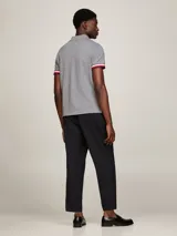 Chomba gris de corte slim confeccionada en algodón orgánico elástico, con cuello clásico, cartera de dos botones, logo de Tommy Hilfiger bordado en el pecho y ribetes distintivos en los puños.