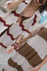 Camisa de tejido de punto oversize con botones en el frente y diseño a rayas horizontales en tonos beige, rojo, marrón y celeste.