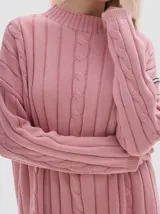 Buzo tejido color blanco, con cuello subido tipo polera, diseño oversized y largo con pequeños cortes laterales.