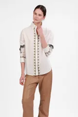 Camisa blanca de poplin de algodón con corte clásico, cuello camisero, cierre frontal con botones, mangas largas con puños abotonados y estampado de triángulos beige en la pechera y estampado de leopardo en las mangas.