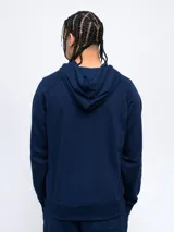 Canguro negro de felpa sin frisa con capucha y logo Umbro bordado en rojo en el pecho. Cuenta con bolsillo tipo canguro y cordones ajustables en la capucha.