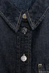 Camisa corta de denim celeste, con cuello solapa, manga larga, bolsillo delantero de plastrón y cierre frontal con botones metálicos.