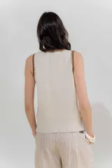 Musculosa de punto color salmón con cuello y sisas ribeteadas en rojo.