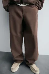 Pantalón negro de corte amplio, confeccionado en tejido de algodón con efecto lavado. Presenta bolsillos frontales, traseros de parche, tira multifunción y bolsillos laterales en las perneras. Cuenta con cierre frontal con cremallera y botón.