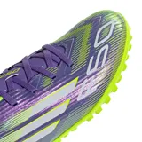 Championes de fútbol 5 Adidas F50 Club en color violeta con detalles en verde lima. Presentan una parte superior sintética con gráficos de velocidad, cierre de cordones y suela de goma con tapones pequeños optimizada para canchas de césped sintético.