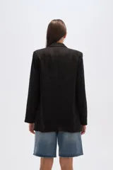 Blazer color beige, de corte holgado, con solapas anchas y bolsillos frontales.