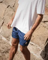 Short de baño azul con estampado de tablas de surf blancas, cintura elástica con cordón ajustable y bolsillos laterales.