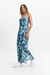 Vestido largo con estampado difuminado en tonos borgoña y blanco, breteles finos regulables y espalda con tiras entrecruzadas. Tiene escote en “V” y tajos laterales.