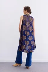 Camisa larga sin mangas confeccionada en viscosa azul con estampado de flores doradas y cuello mao. Presenta bordados en cuello y cartera frontal, y cierre frontal con cremallera.