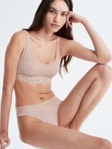 Colaless color beige con encaje floral semitransparente y cintura elástica con logo Calvin Klein.