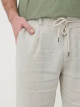 Pantalón capri de lino color beige con efecto melange, pretina elástica con cordón ajustable, bolsillos delanteros y traseros.