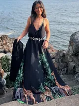 Vestido largo negro con estampado de jungla con palmeras, jirafas y leopardos. Tiene breteles finos, escote en V cruzado y cinturón con apliques brillantes.